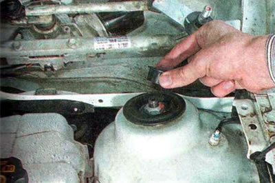 7. Поддеваем шлицевой отверткой и снимаем защитную крышку гайки верхнего крепления амортизаторной…