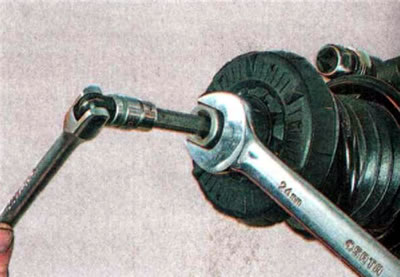 19. Ключом на 24 мм отворачиваем гайку штока амортизатора, удерживая шток от проворачивания ключом…