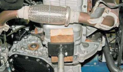 ...din partea din spate a motorului, folosind un cap de 10 mm, slăbiți șurubul care fixează…