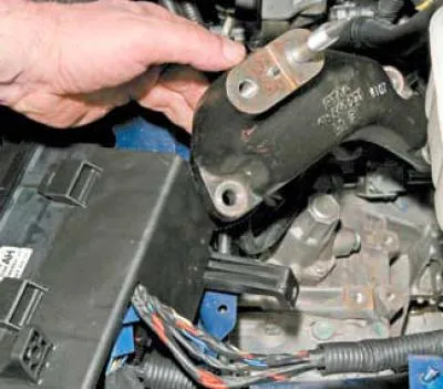 Folosind o priză de 14 mm cu prelungire, deșurubați cele trei șuruburi care fixează suportul de…