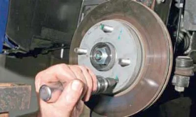 Koristeći žičanu četku, očistite prljavštinu i koroziju s glave vijka koji pričvršćuje disk kočnice…
